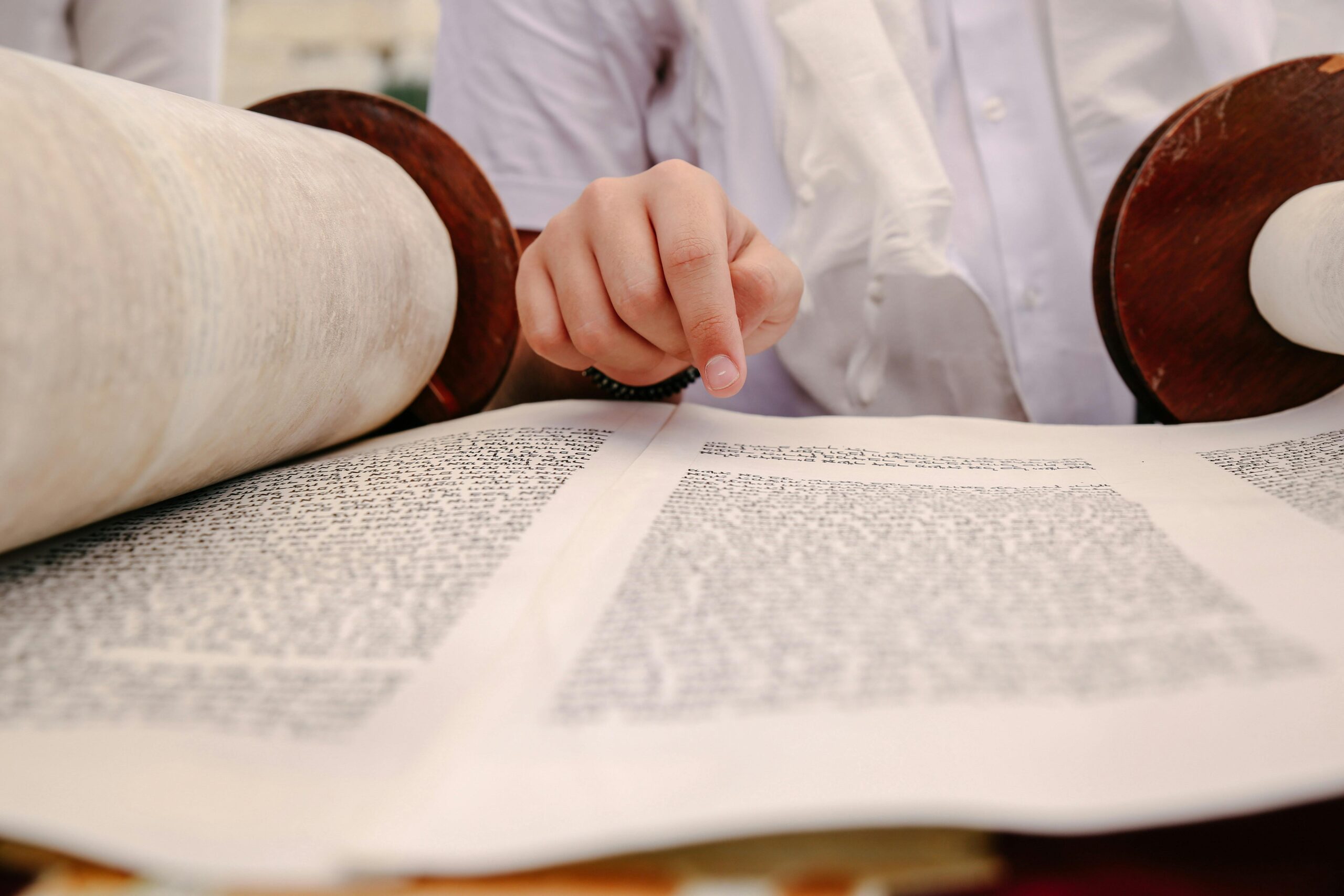 A hand pointing at text on an open Torah scroll, symbolizing Jewish tradition.