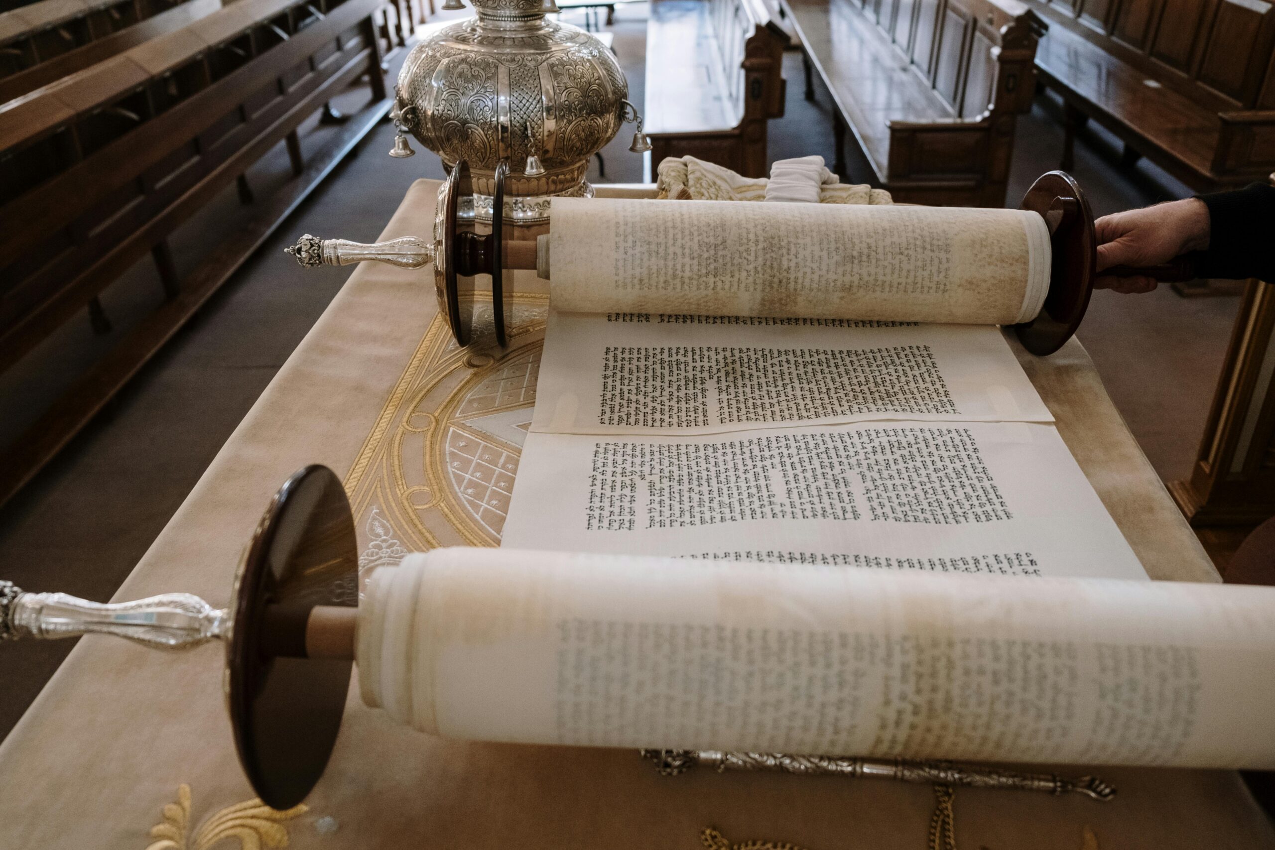Detailed view of an open Sefer Torah with visible Hebrew script inside a synagogue.