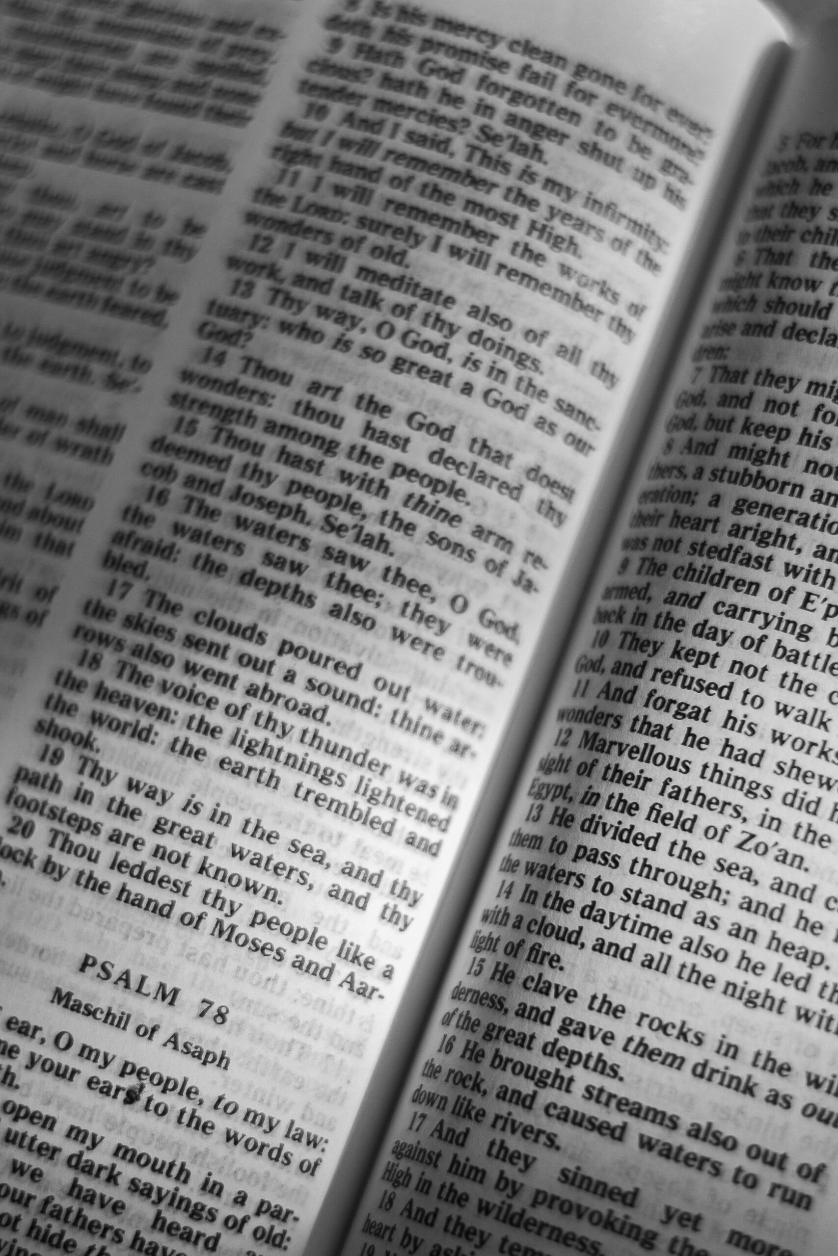 A close-up black and white image of an open Bible displaying Psalms, focusing on scripture.